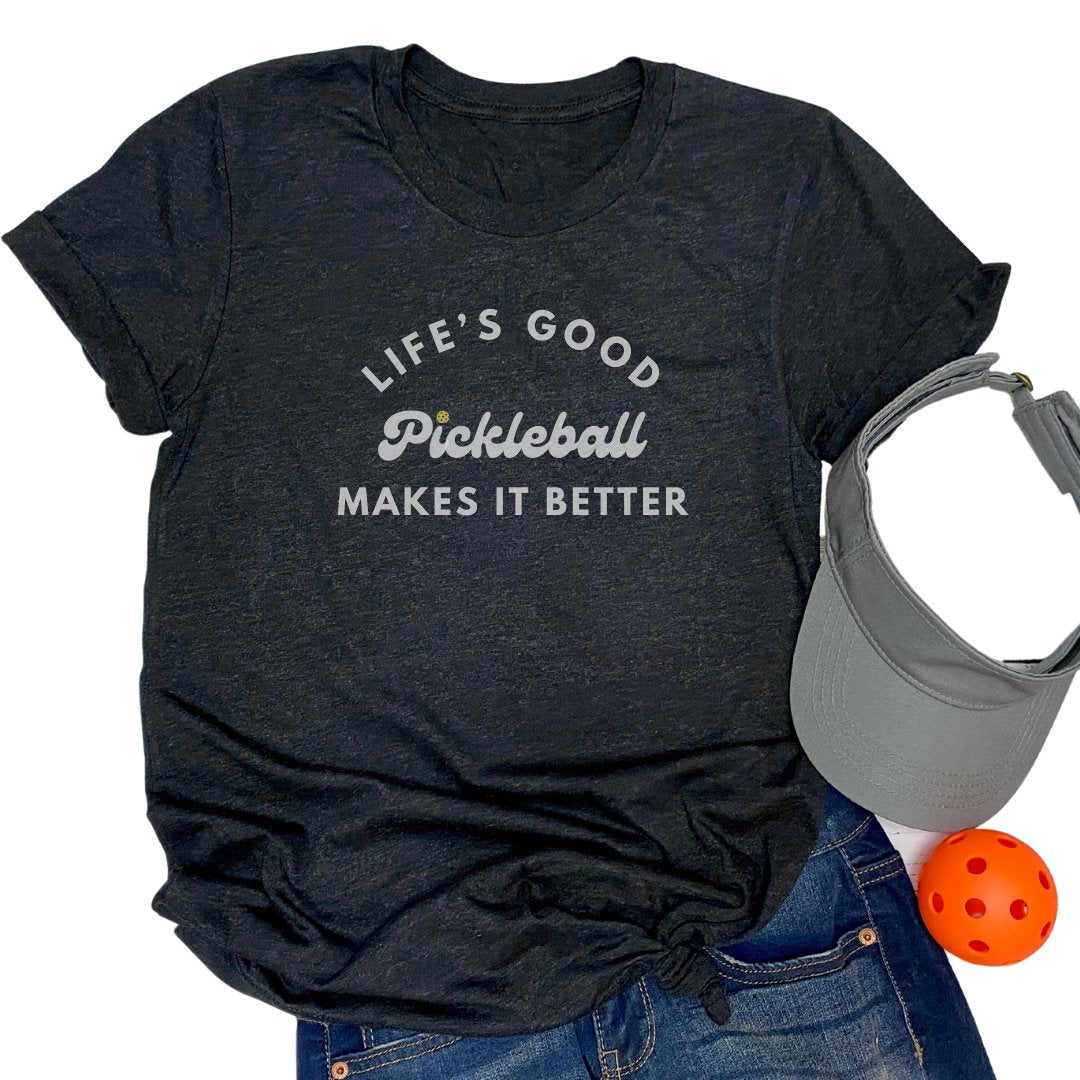 senior woman wearing sand sweatshirt with the words life's good pickleball makes it better