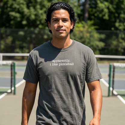 Man wearing a pepper gray Comfort Colors t-shirt that says apparently i like pickleball on a pickleball court