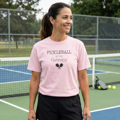 Woman wearing a pink 'Pickleball is my therapy' comfort colors pickleball shirt on a pickleball court.