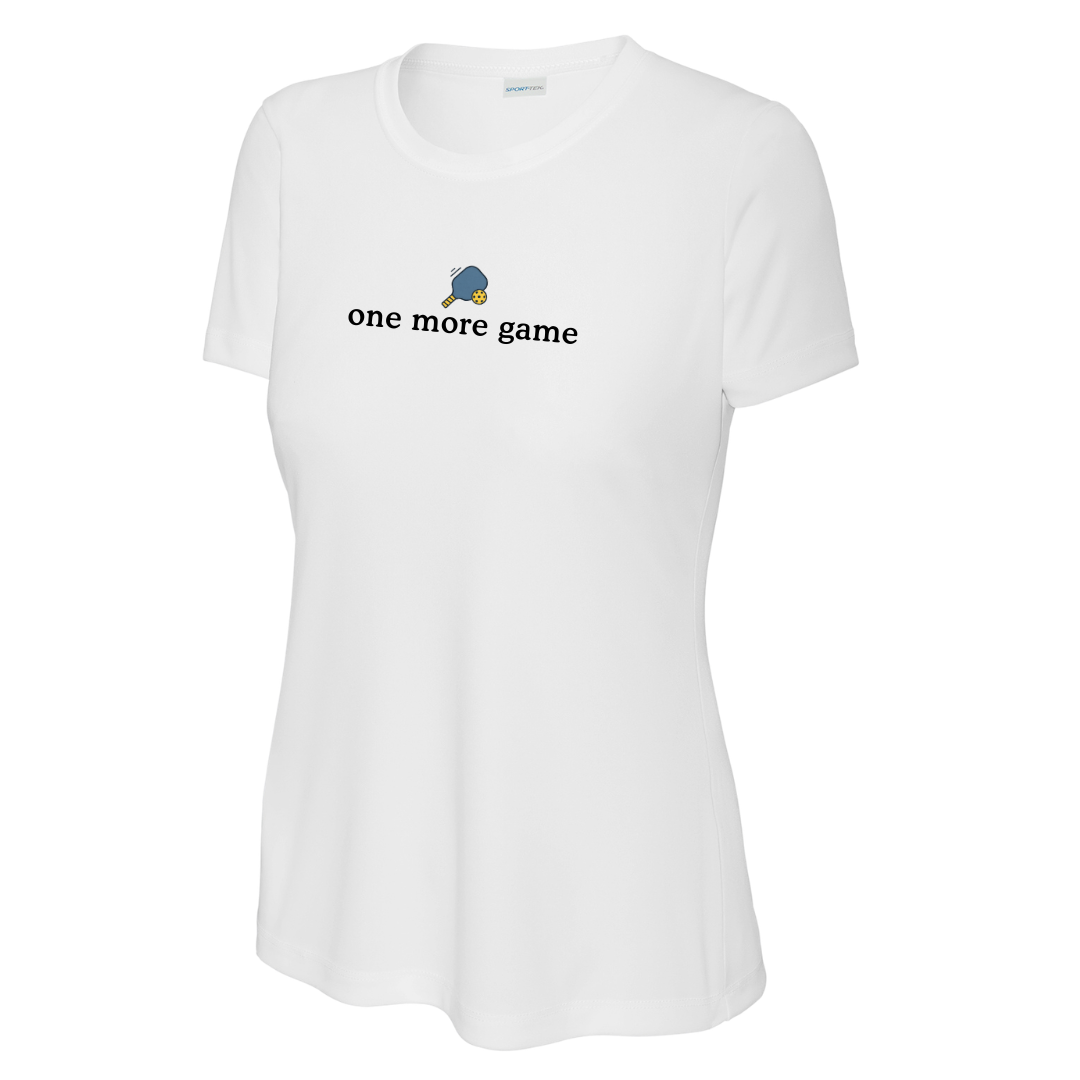 A white short-sleeve crewneck pickleball t-shirt with a graphic on the chest featuring a blue pickleball paddle and yellow pickleball and the text 'one more game' in black