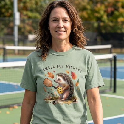 Woman wearing a green pickleball t-shirt with a hedgehog graphic on a pickleball court